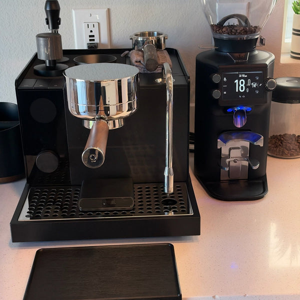 Black E64 WS beside an espresso machine on white quartz