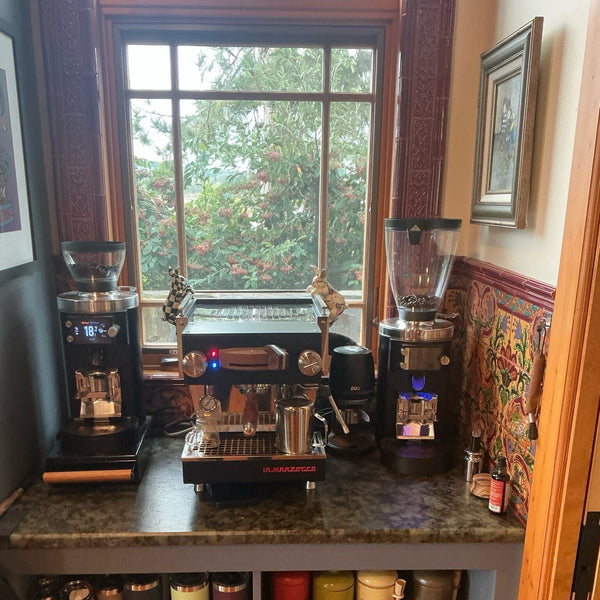 Two grinders and a Linea Micra under a garden window